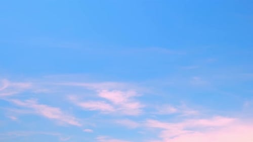 Pink clouds drifting in light blue sky