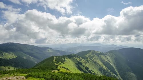 White Clouds over Blue Sky Flying over Green Landscape in Mountains