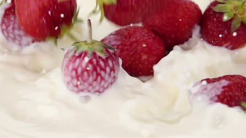 Fresas maduras que caen en la leche
