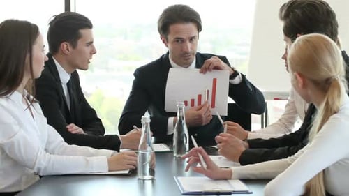 Business Team Meeting at Table Discussing Graphs