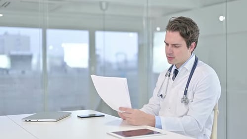Jeune médecin travailleur lisant des documents au bureau