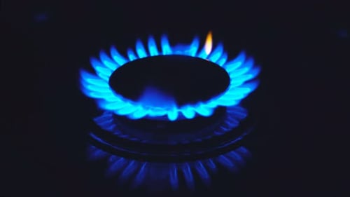 Brenner auf dem Herd, der sich in eine blaue Kochflamme entzündet.