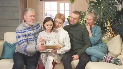 Família extensa e amigável assistindo fotos do tablet