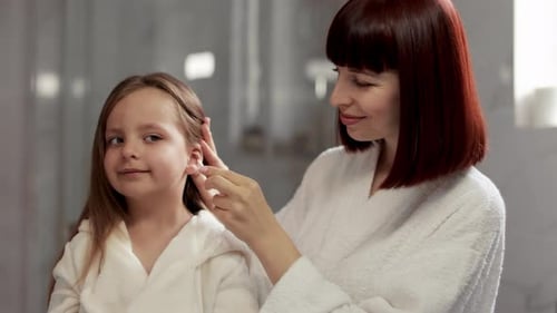 Woman Cleans Young Girl's Ears in Bathroom
