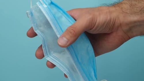 Hand Crushing a Light Blue Surgical Mask