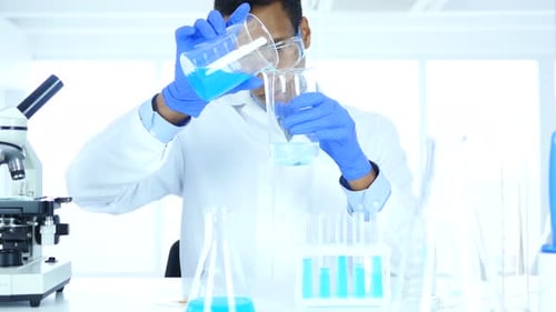 Young Adult Scientist Mixing Chemicals in Beakers