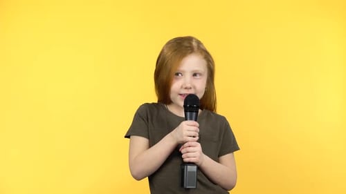 Child Singing Into Microphone on Yellow Background