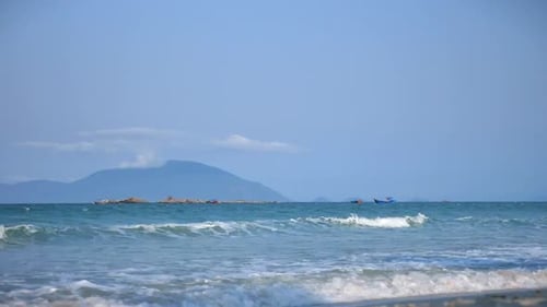 Wunderschöne Meereswellen mit großem Meeresschaum vor dem Hintergrund der Insel und zwei asiatischen Booten