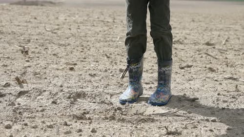 Child Digging in Field With Shovel