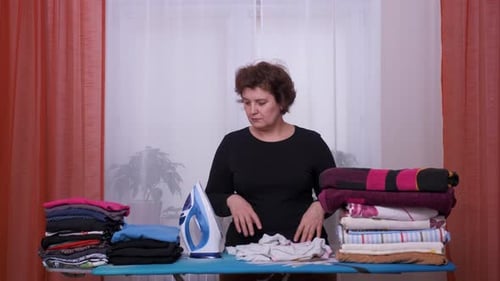 Tired Woman Ironing Clothes at Home