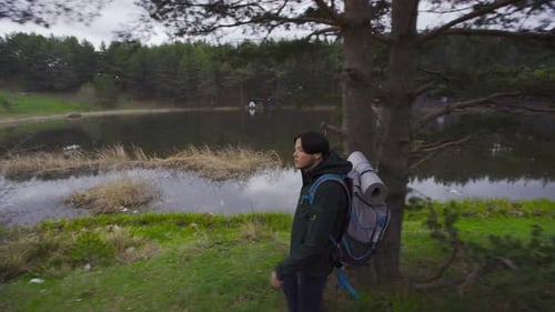 Young Adult Hiking with Backpack Near Lake
