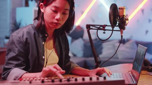 Asian Female Musician Using Sound Mixer and Laptop in Home Recording Studio