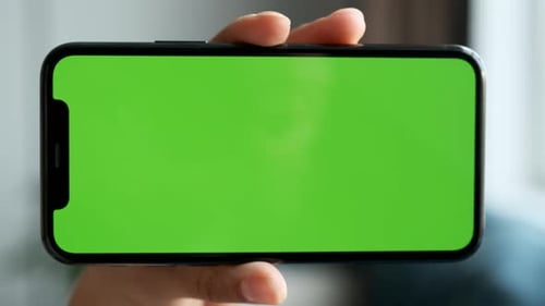 Close-Up Of A Woman's Hand Holding Horizontally A Smartphone with A Green Screen