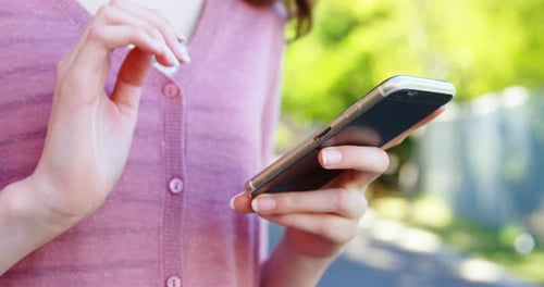 Woman Using Smartphone Outdoors on Sunny Day