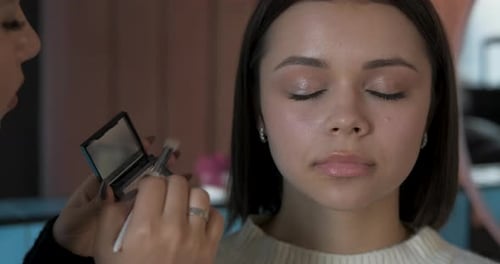 Nahaufnahme einer Visagistin bei der Arbeit mit dem Augenlid des Kunden Junge Frau bei Procedere in the Beauty