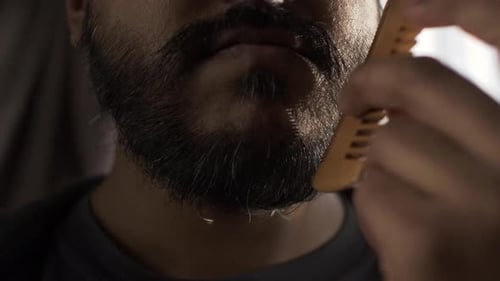 Close Up Of Ethnic Minority Adult Male Combing Beard. Locked Off , Half Face View