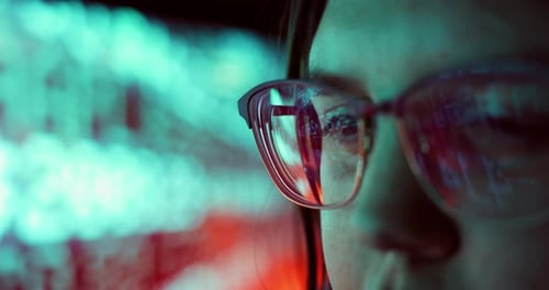 Gros plan d'une jeune femme adulte portant des lunettes réfléchissantes analysant les données du code de cybersécurité