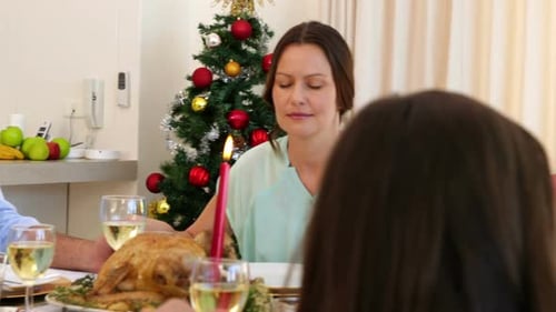 Família extensa pedindo graça antes da ceia de Natal