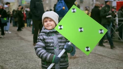 Young Child Holds Tracking Sign in City Street