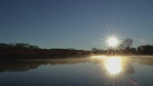 Fog Slowly Rolls Across a Lake at Sunrise Wide Shot