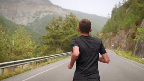 Young Adult Running on Road in Mountain Scenery
