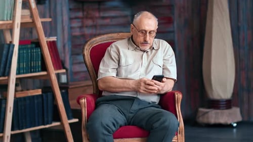 Senior Man Using Smartphone in Armchair