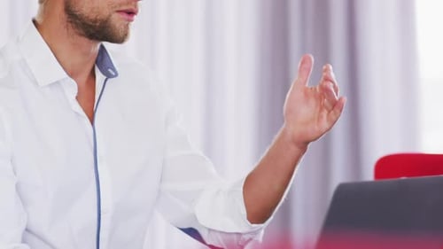 Professional businessman with laptop talking while sitting in modern office in slow motion