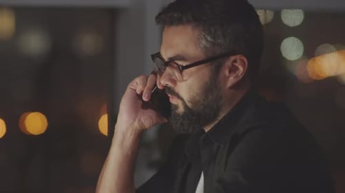 Businessman Talking on Phone in Dark Office