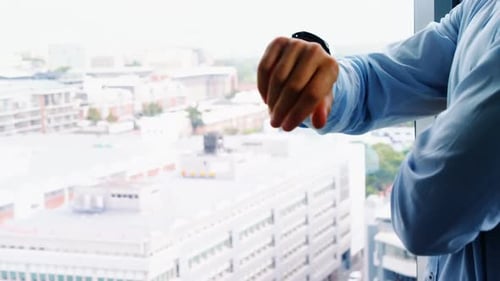 Executive checking time while standing near window