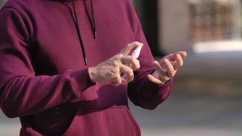 Person Sprays and Rubs Hand Sanitizer on Hands