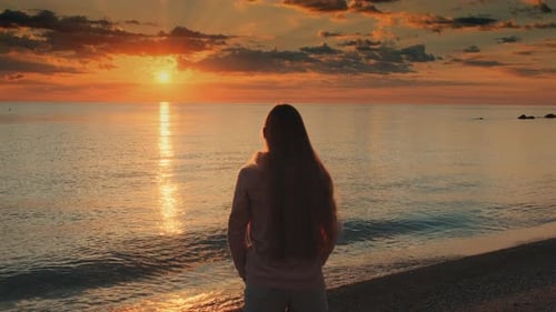 Woman with Outstretched Arms Enjoying the Beauty of Sunset on the Sea