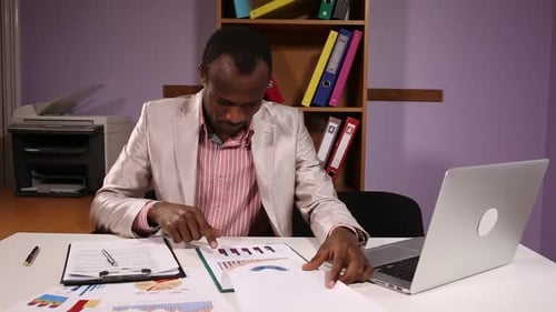 Adult Man Reviews Charts at Modern Office Desk