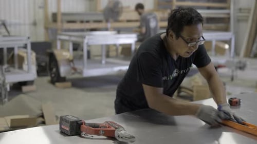 Worker marks sheet metal for cutting