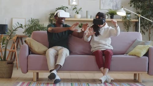 Couple Experiencing Virtual Reality Headsets on Couch
