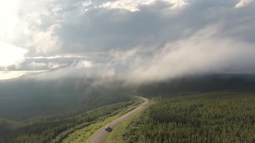 Beautiful View of Scenic Road From Above Surrounded By Lush Forest, Clouds and Mountains
