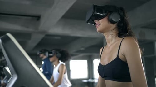 4K Athletic man and woman wearing VR glasses jogging exercise on treadmill at fitness gym.