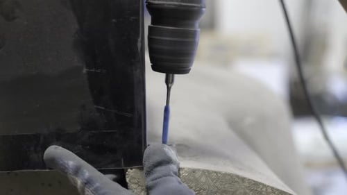 Workman drilling a hole into oven in workshop