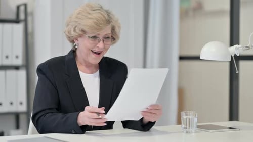 Woman Reviews Paperwork with Positive Reaction in Office