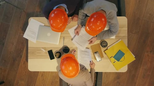 Workers Collaborate Wearing Hard Hats in the Office