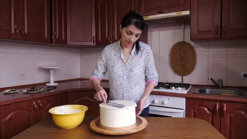 Woman Decorating Cake With Frosting In Kitchen