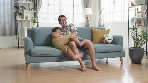 Father and Son Laughing Together Watching TV