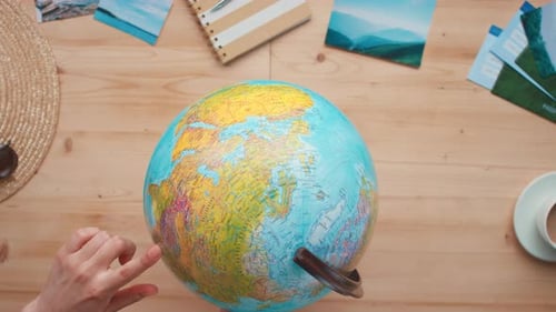 Hand Planning Travel Route with World Globe