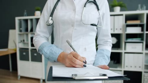 Nahaufnahme der Hand eines Arztes, der in die Krankenakte des Patienten schreibt und im Krankenhaus arbeitet