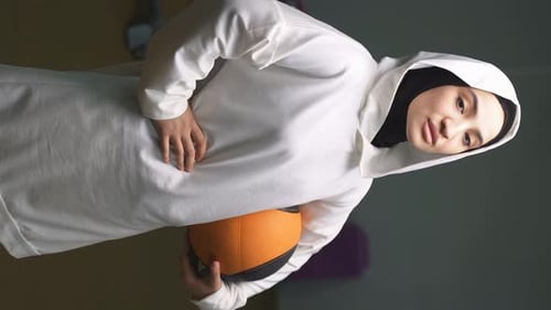 Smiling Woman Holding Basketball in Gymnasium
