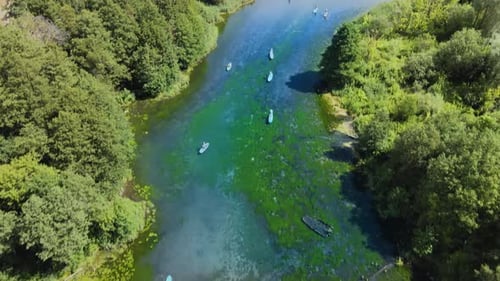Group of paddlers are paddling along azure river. Vacationers enjoy the beauty