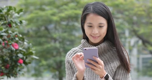 Woman Using Smartphone in Urban Garden Setting