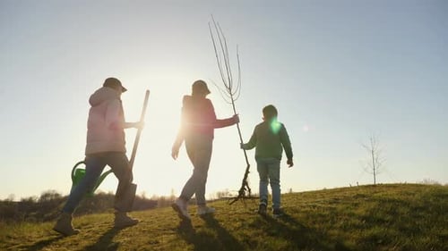 Mom with Two Children Going to Plant a Tree