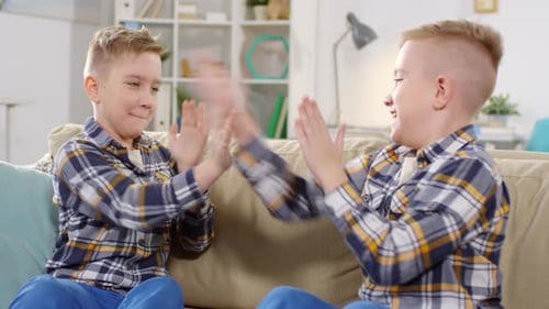 Irmãos gêmeos jogando palmas em casa
