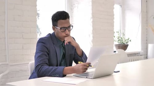 African Man Reading Documents and Brainstorming