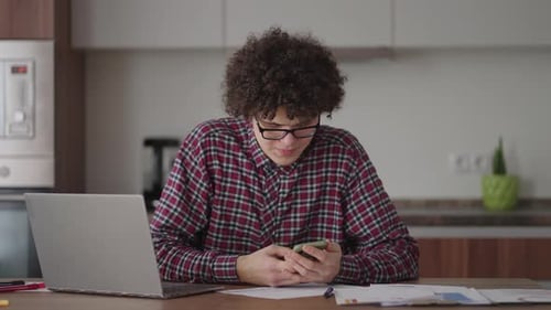 Young Adult Using Laptop and Cellphone at Home